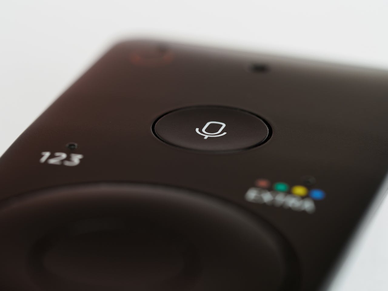 Close-up of a remote control featuring a prominent microphone button, suitable for voice commands.